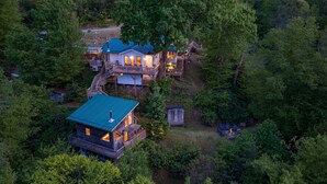 A cabin with a deck, surrounded by dense forest. - Amazing View! Sauna Gameroom Firepit Spa Room Rustic Spacious Private Retreat  (Banner Elk)