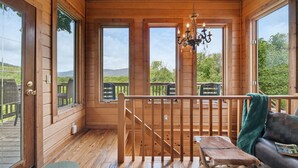 A wooden cabin with large windows, a chandelier, and a deck with outdoor seating. - Amazing View! Sauna Gameroom Firepit Spa Room Rustic Spacious Private Retreat  (Banner Elk)