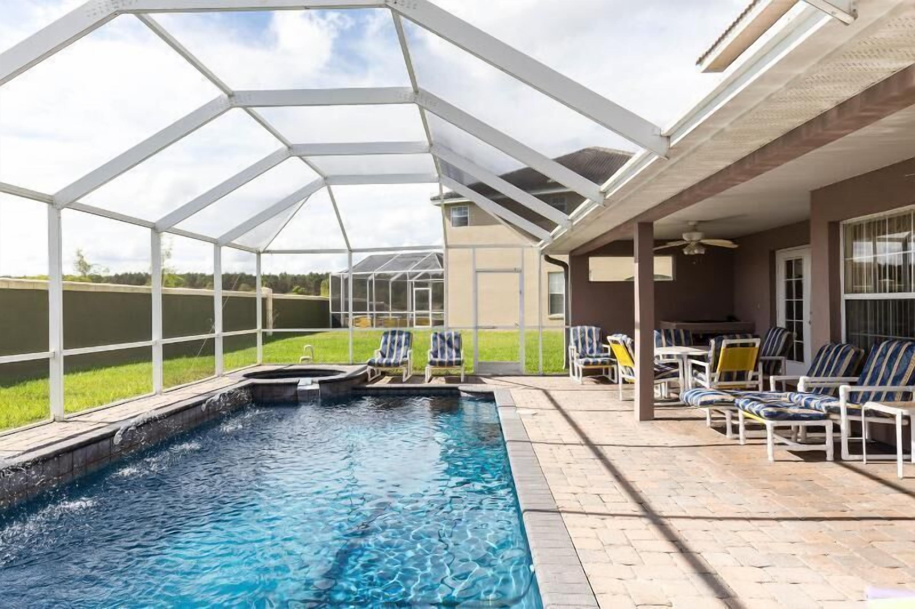 Ein Schwimmbecken mit Glasüberdachung, Liegestühlen und einer Terrassenanlage.