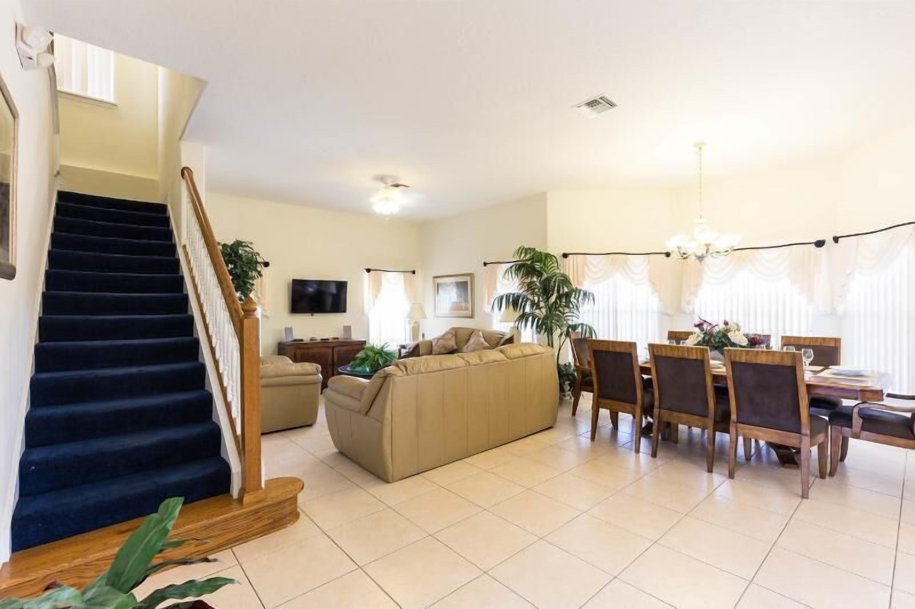 A living room with a sofa, dining table, chairs, and a staircase.