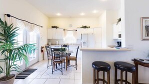 A modern kitchen with white cabinets, a central island, and bar stools.