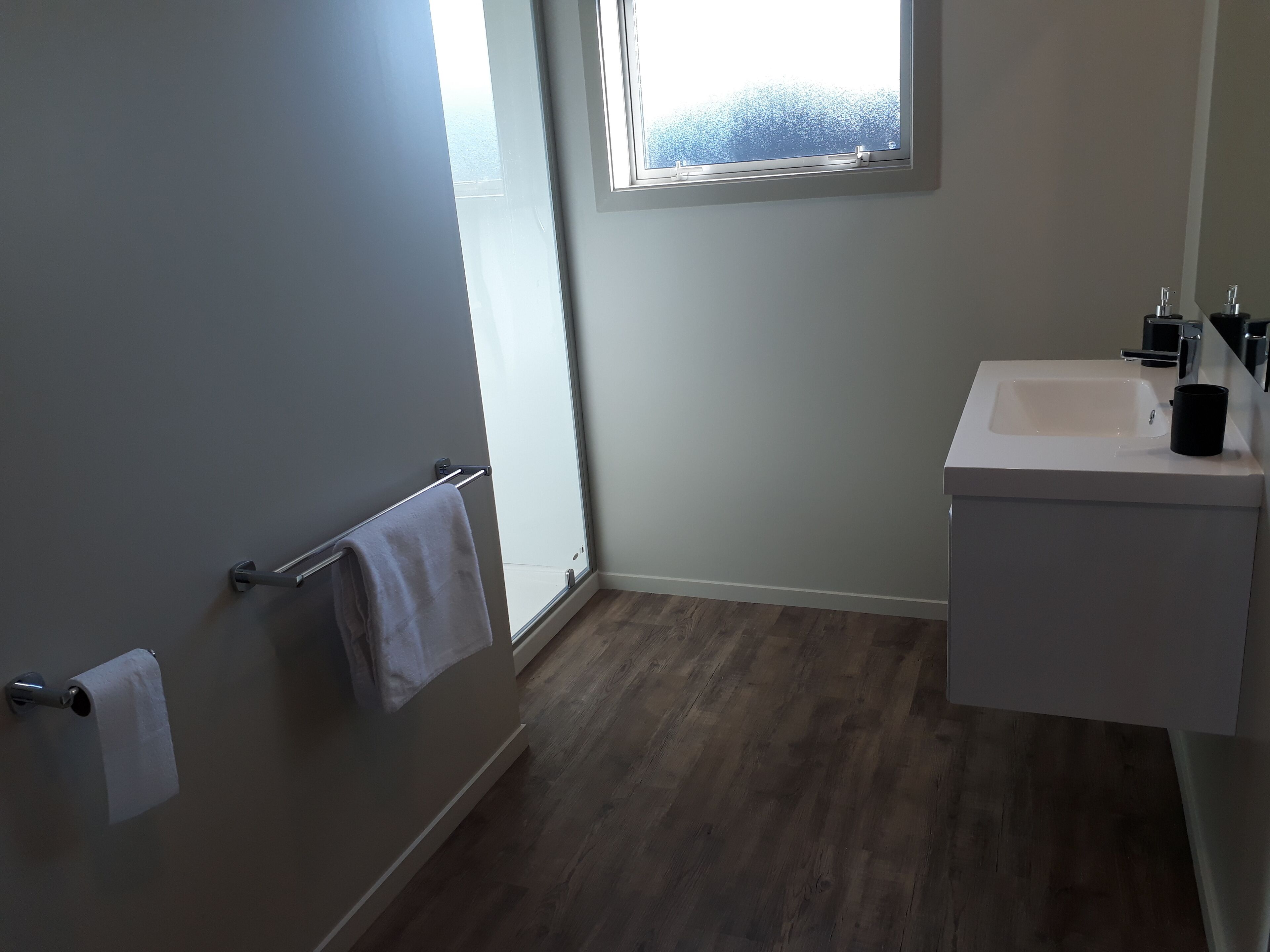 Un bagno con lavandino bianco, portasciù asciugamani e una finestra vista mare.