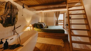 A bedroom with a wooden ladder, a bathtub, and a bed with pillows.