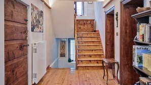 A wooden staircase in a hallway with a radiator, a wooden door, and a bookshelf with books. - Typical Cadore house, 15 minutes from Cortina, 4 big bedrooms and 3 bathrooms  (Vodo Di Cadore)