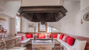 A cozy room with a stone fireplace, a wooden bench with red cushions, and a wooden cabinet with wine glasses. - Typical Cadore house, 15 minutes from Cortina, 4 big bedrooms and 3 bathrooms  (Vodo Di Cadore)