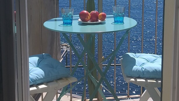 Un balcon avec une table et des chaises, donnant sur la mer.
