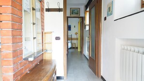 Un pasillo con pared de ladrillo, un banco de madera, un radiador y una puerta que da a otra habitación.