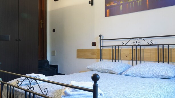 Un dormitorio con cama, armario, un cuadro en la pared y cabecera de madera.