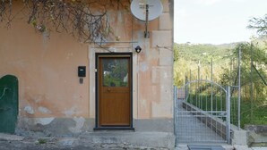 Un edificio con puerta de madera, antena parabólica y un portón que da a una escalera.