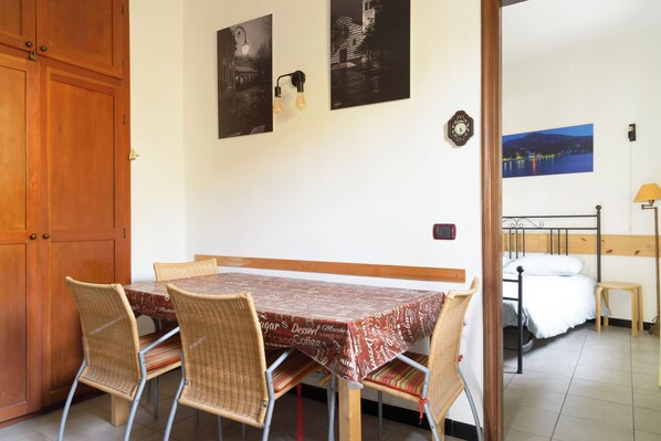 Un comedor con una mesa y sillas, una puerta de madera y una cama en la habitación contigua.