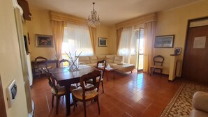 Un área de comedor con una mesa y sillas, un sofá y una araña.