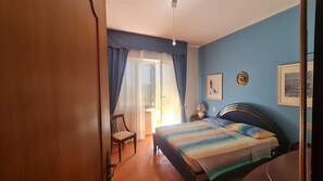 Une chambre à coucher comprenant un lit, une chaise, une table de chevet et deux tableaux encadrés accrochés au mur.