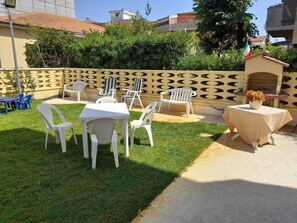 Une terrasse extérieure avec une table et des chaises, un petit coin barbecue et une clôture décorative.