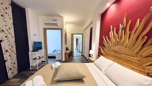 Habitación de hotel con una cama grande, cabecera de madera, televisor y vista al mar.