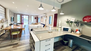 Una cocina moderna con una isla central, electrodomésticos integrados y una zona de comedor con suelo de madera.