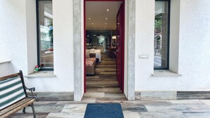Una entrada moderna con un banco de madera, un tapete azul y vistas a un área de comedor con una puerta roja.