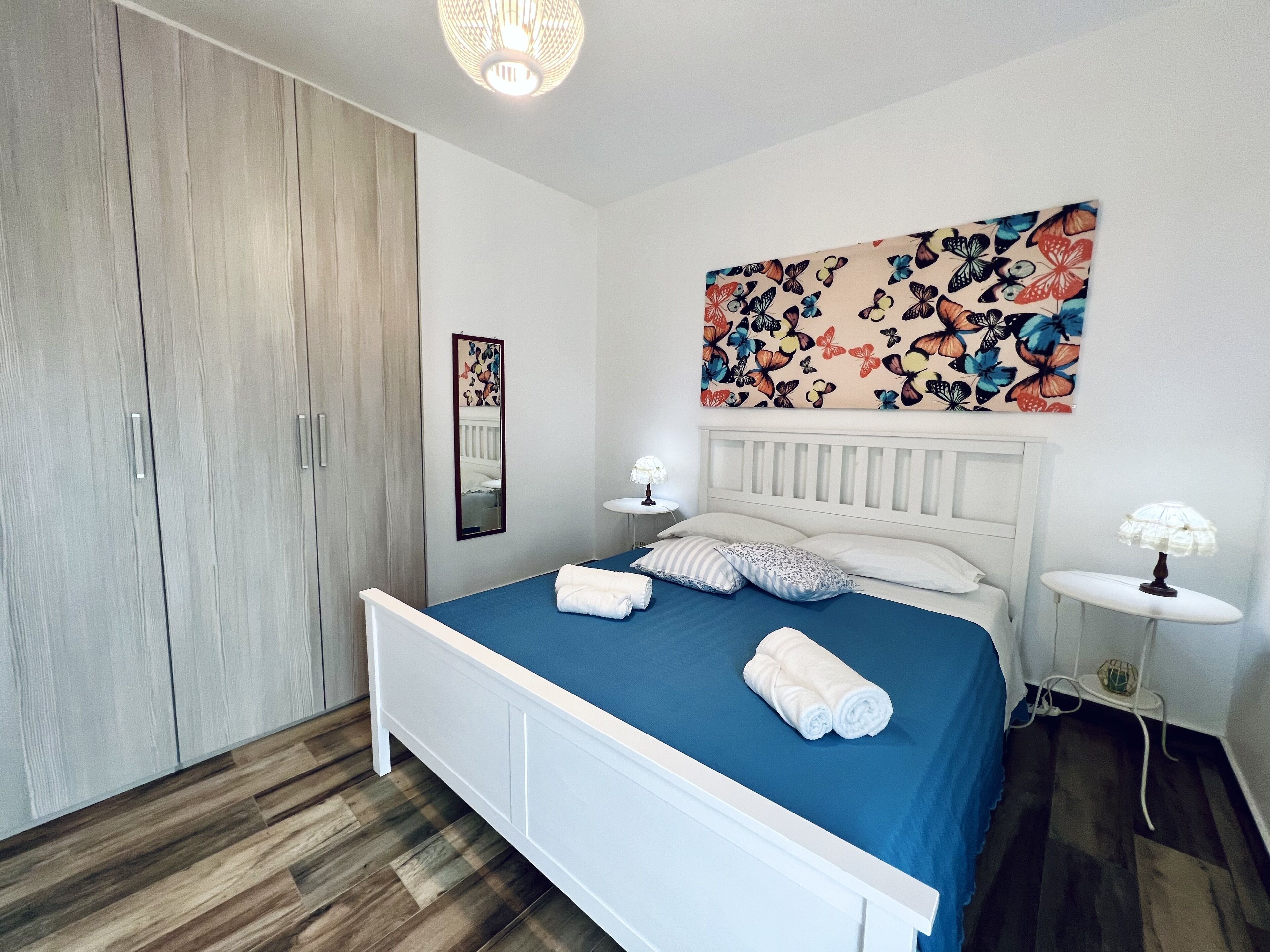 Une chambre à coucher comprenant un lit, des tables de chevet, une armoire et une décoration murale à motifs floraux.