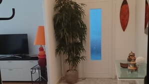 Un pasillo con una planta en maceta, un televisor y una mesa con adornos.