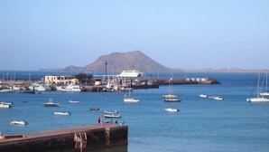 Ein Yachthafen mit vertäuten Booten, einer Mole und einem Berg im Hintergrund.