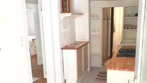 A narrow hallway with wooden flooring leading to a kitchen area with white cabinets and a small countertop. - Romantic, listed holiday apartment in Freiburg-Herdern on the church square (Nord)