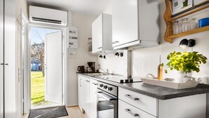 A modern kitchen with white cabinetry, a built-in oven, and a countertop with a coffee maker.