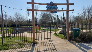 Une entrée sécurisée donnant accès à un parcours d’Aqua Golf, avec un panneau indiquant la présence d’un espace de mini-golf et d’un service de location de vélos.