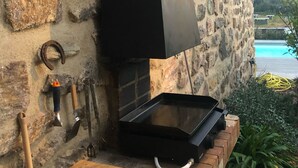Un mur de pierre avec une grille noire et un banc en bois.