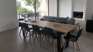 Un salon moderne avec une grande table à manger, des chaises noires, un canapé gris et une cheminée.