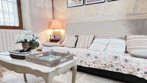 A cozy bedroom with a bed, pillows, a bedside table, a lamp, and a window with lace curtains.
