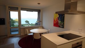 Een moderne keuken met een groot raam, een eethoek met een ronde tafel en uitzicht op zee.