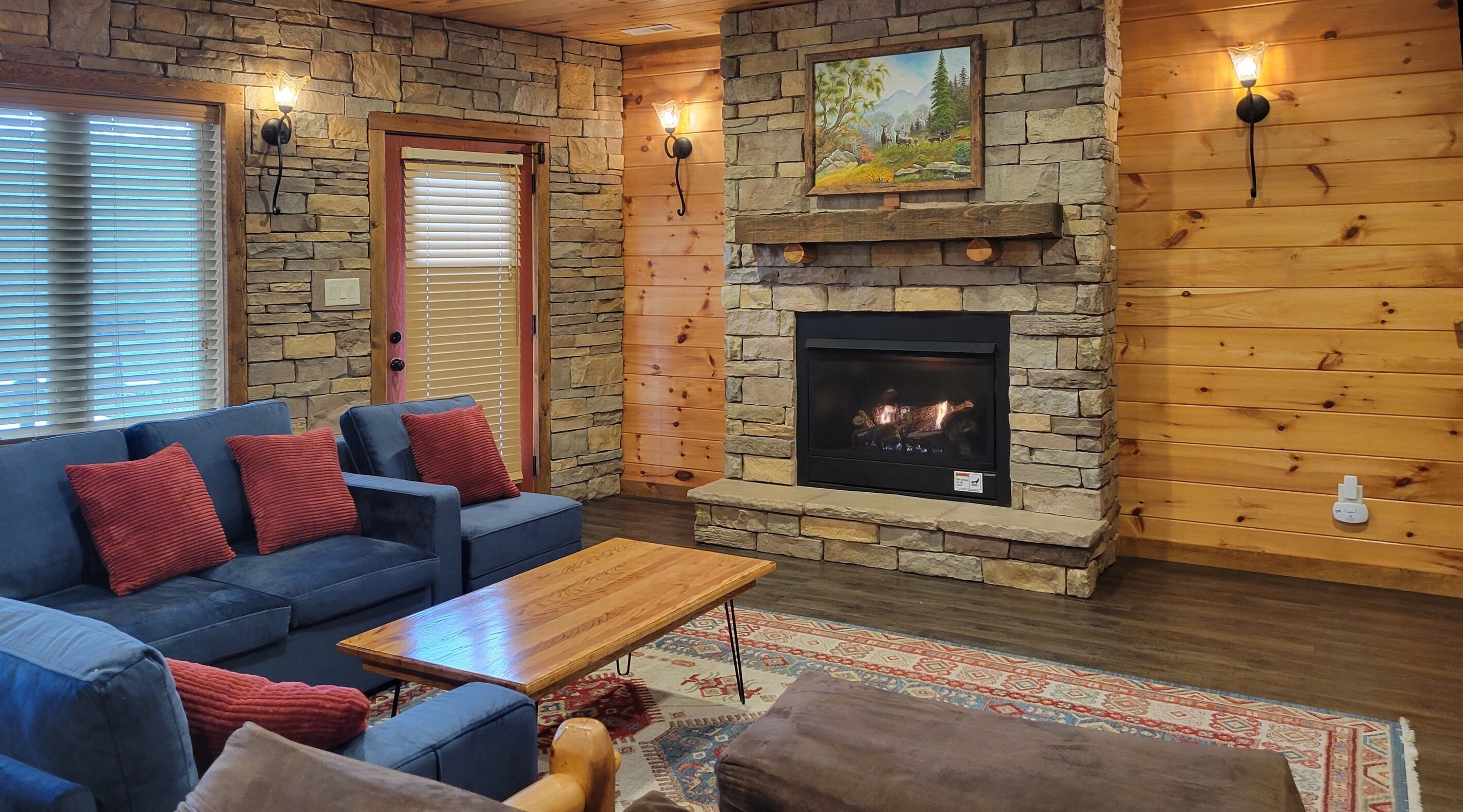A cozy living room with a stone fireplace, blue sofa, and a wooden coffee table.
