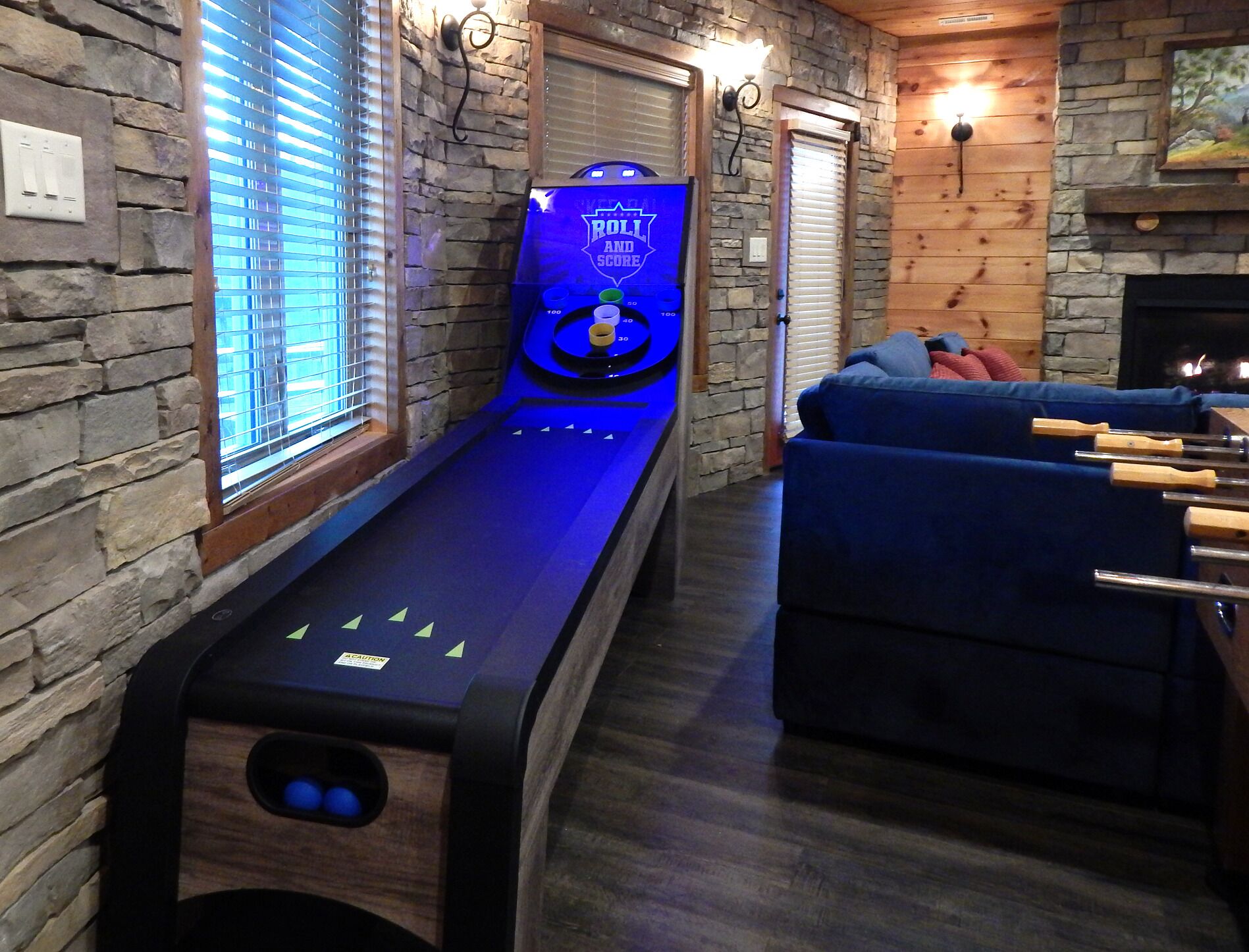 A billiards table with a digital scoreboard in a room with stone walls and a fireplace.