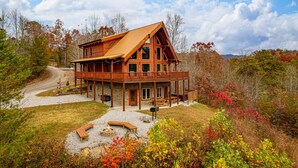 A large wooden cabin with a wrap-around porch, a fire pit, and a gravel driveway. - Ridge View Lodge • Nature/Mtn View • Hot tub • Firepit • Games • Parking 6 cars (Sevierville)
