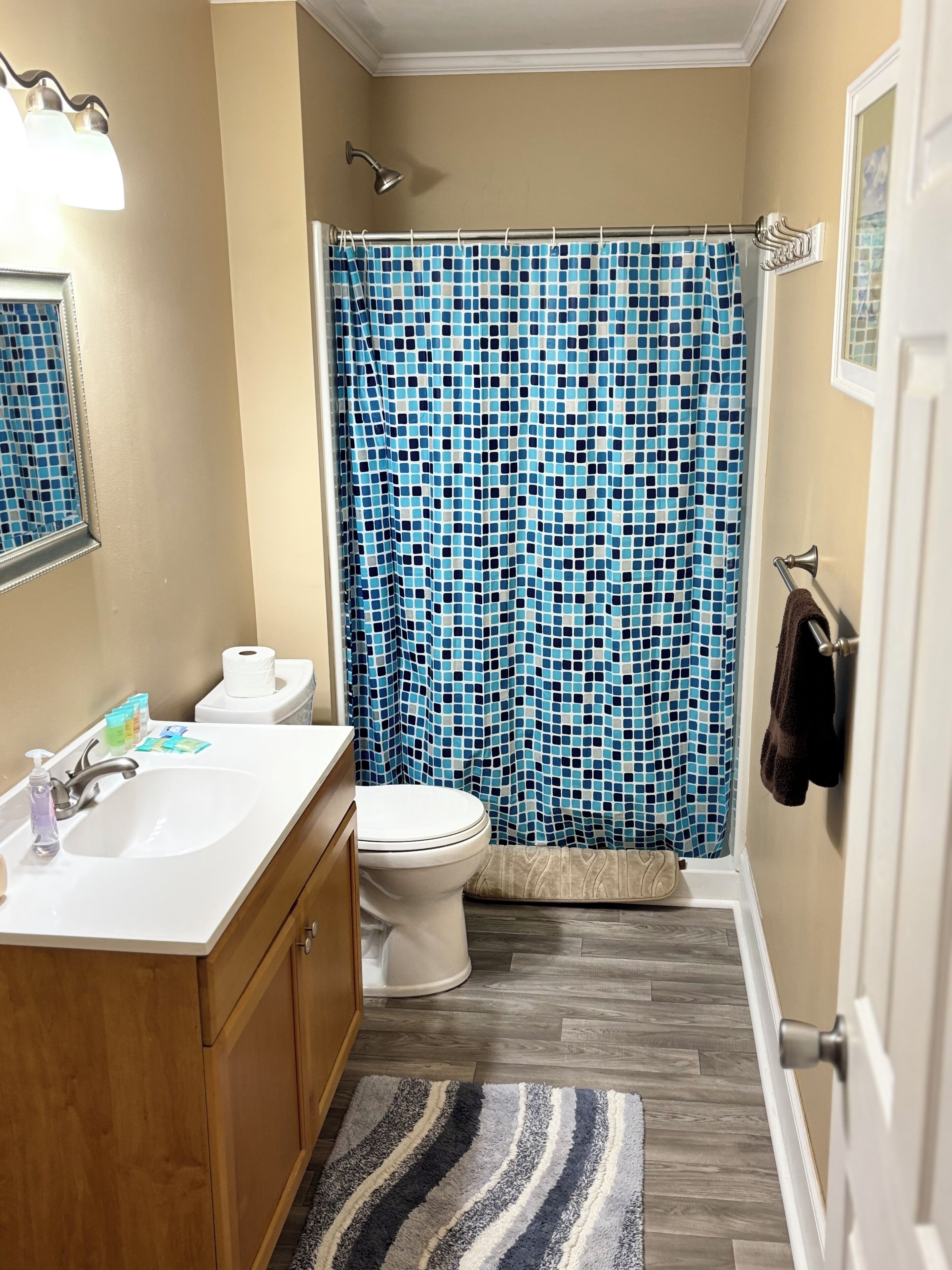 A bathroom with a white sink, toilet, and a shower curtain with a blue mosaic pattern.
