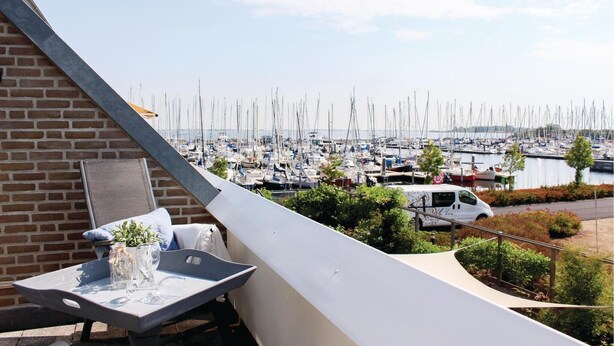 Ein Balkon mit Tisch für zwei Personen mit Blick auf einen Hafen voller Boote.