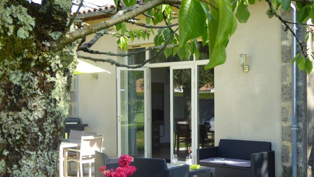 Eine Terrasse im Freien mit Essbereich, einer Couch und einem Blumentopf.