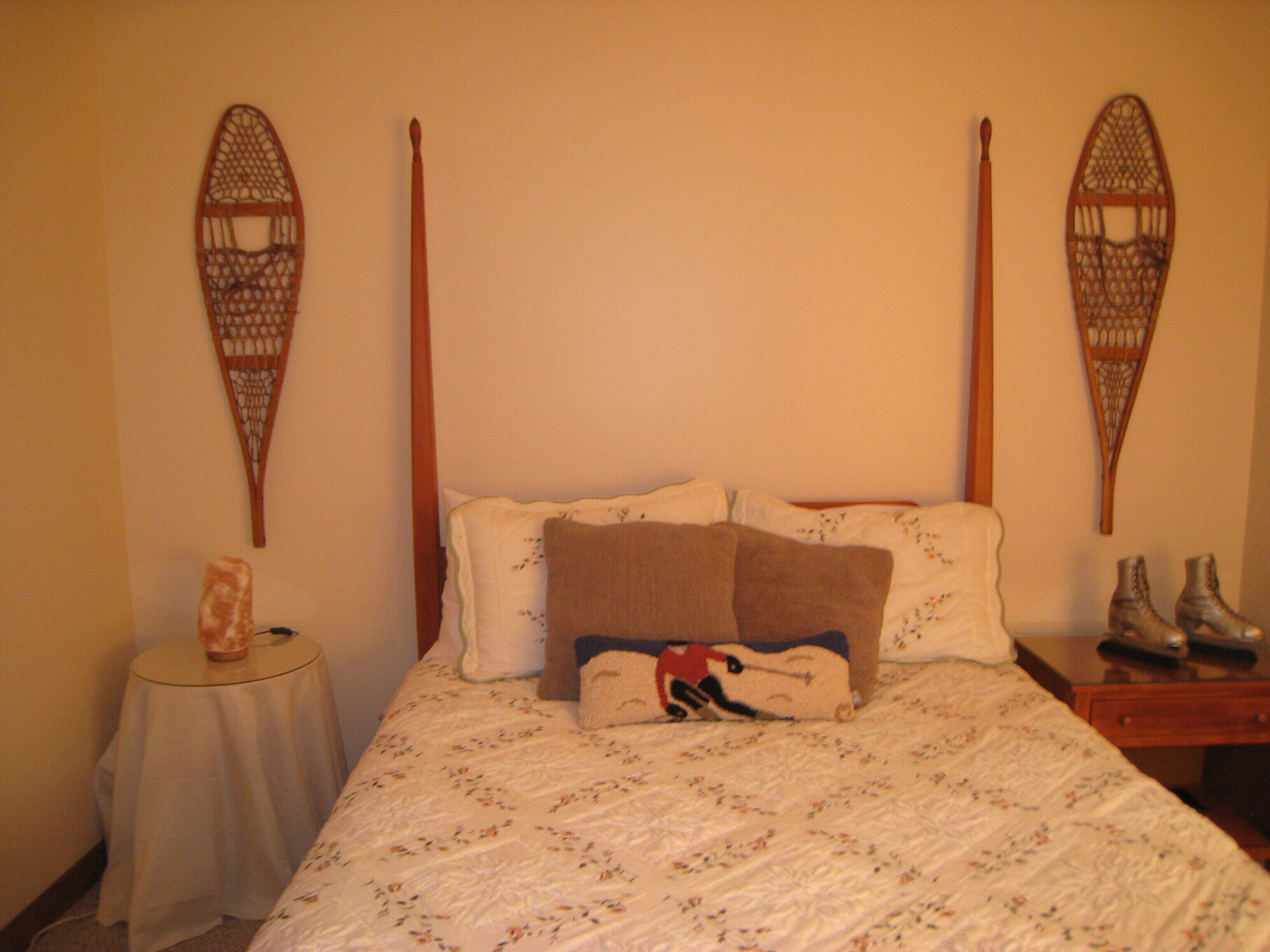 A bedroom with a bed, pillows, a bedside table, and a wall-mounted decorative item.