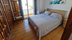 Ein Schlafzimmer mit einem Bett, einem Sessel, einem Gemälde und einer Schiebetür zum Balkon.