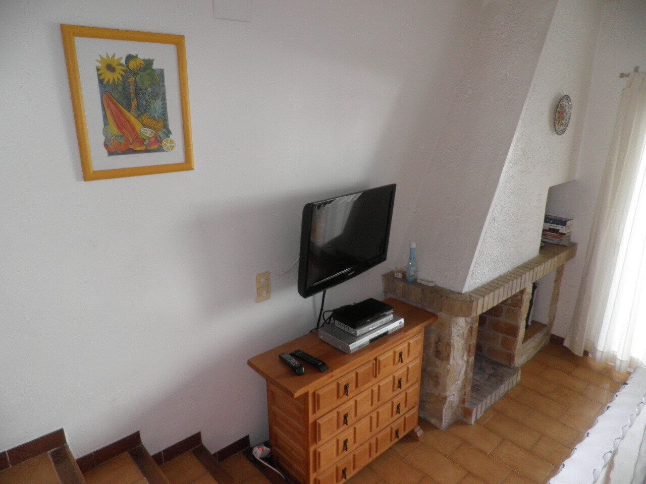A living room with a television, a fireplace, and a wooden cabinet.
