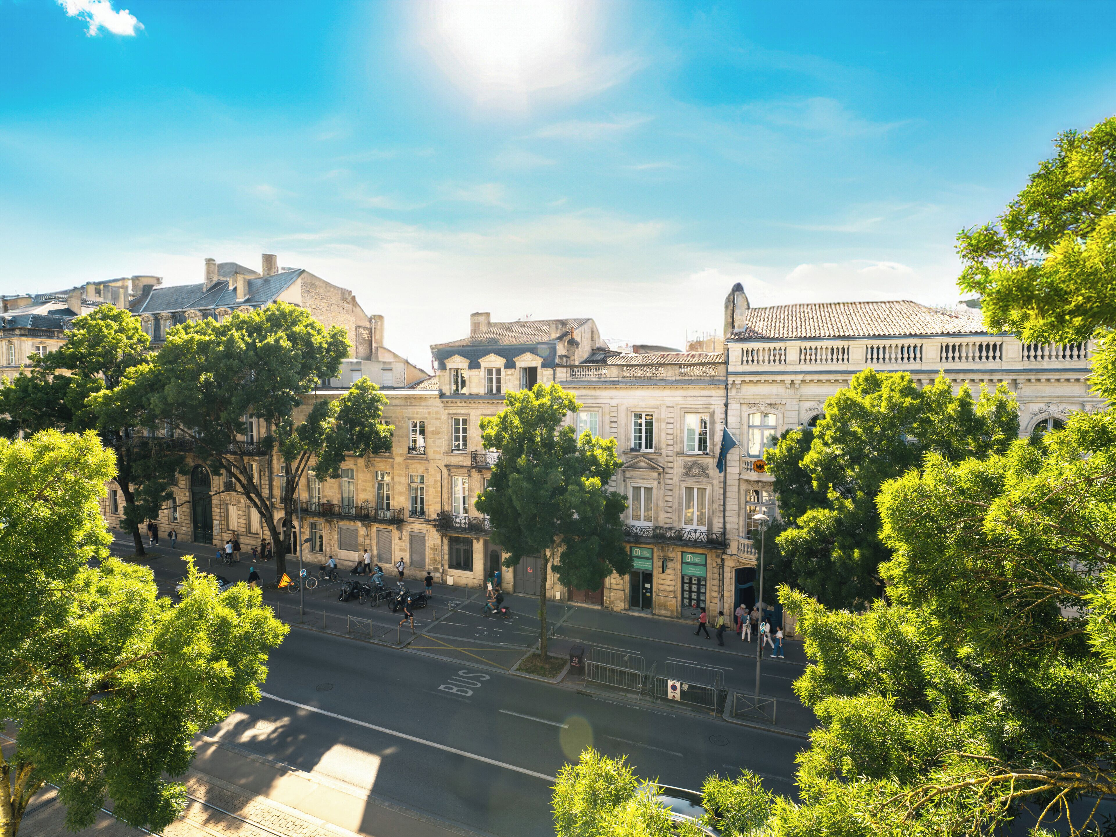A street view with historic buildings, a clear sky, and trees.