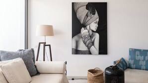 Een moderne woonkamer met een bank, een vloerlamp, een bijzettafeltje en een kunstwerk aan de muur.