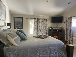 Relax in this inviting bedroom with a large bed, flat-screen TV, and cozy fireplace.