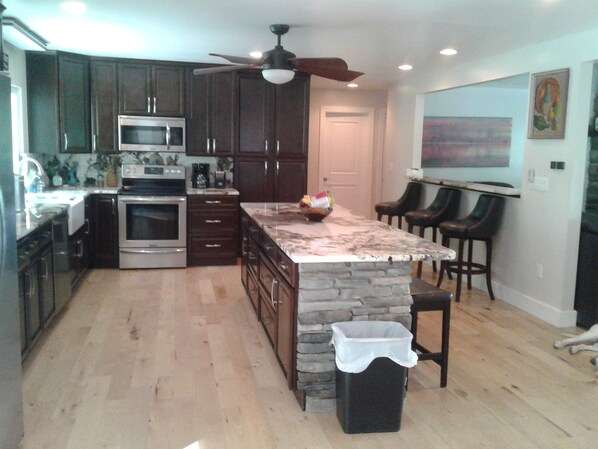Enjoy cooking in this well-equipped kitchen with a large island, dark cabinetry, and stainless steel appliances.