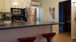 Een moderne keuken met witte kastjes, roestvrijstalen apparatuur en een blauw aanrecht.