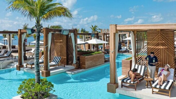Ein Poolbereich mit Liegestühlen und Holz-Pergolen.