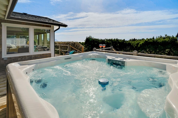 Un jacuzzi con muelle de madera y sala con paredes de vidrio.