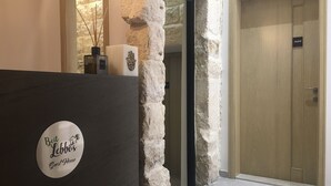 A reception area with a stone pillar, a sign reading "Beit Lebbos Guest House," and a wooden door in the background. - Beit Lebbos (Beit Al Dine)
