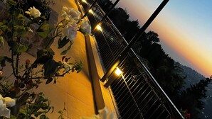 A terrace with a canopy, potted plants, and a view of the sunset. - Beit Lebbos (Beit Al Dine)