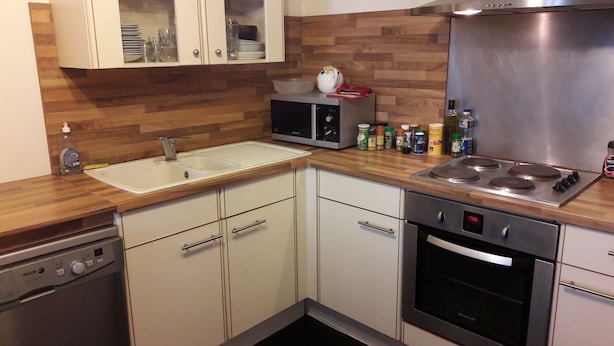 A compact kitchen with a sink, microwave, stove, oven, and cabinets.