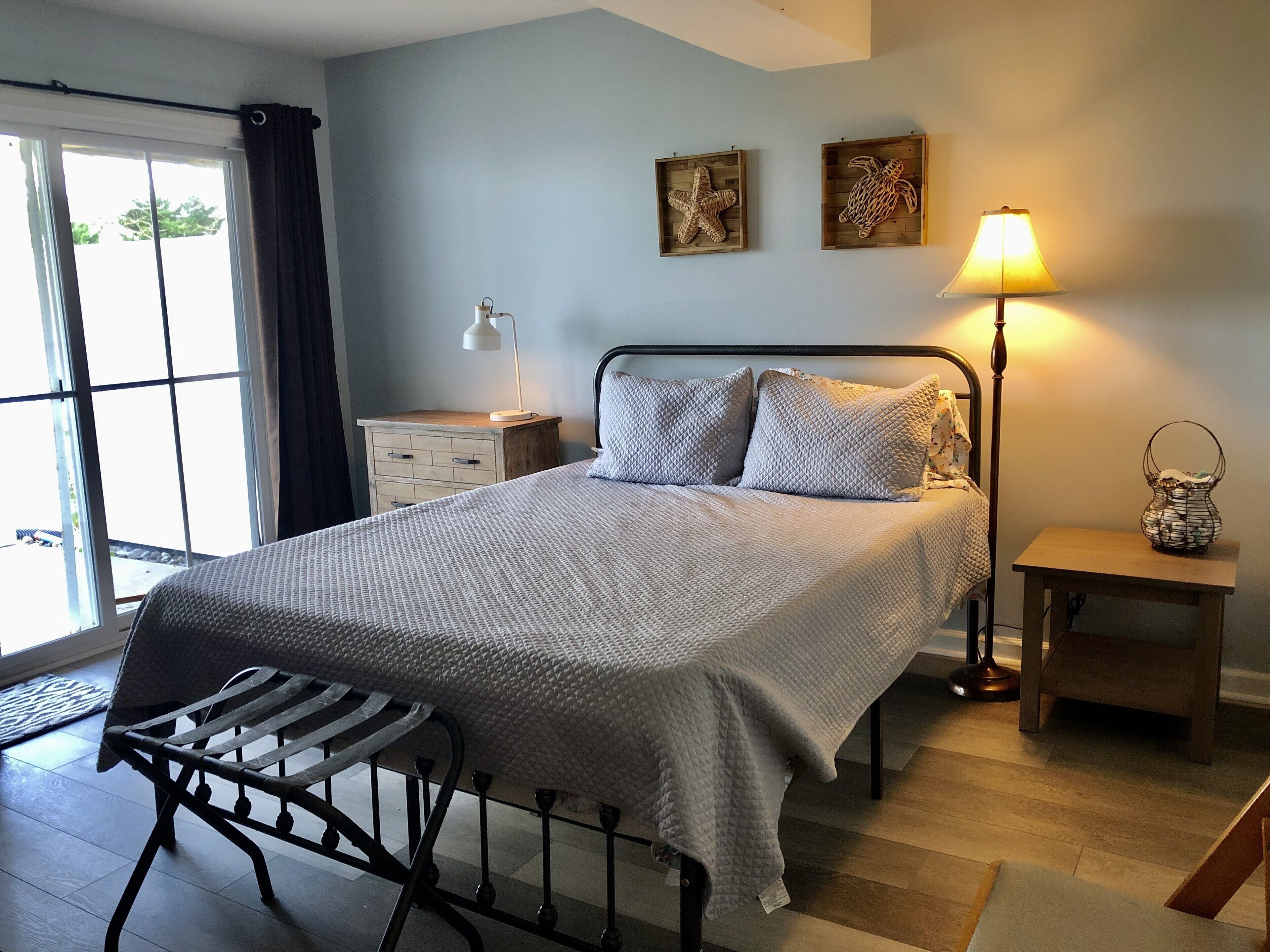 A bedroom with a bed, bedside tables, a lamp, and artwork on the wall.